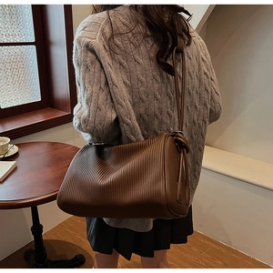 Detail of soft brown pleated shoulder bag showing vertical textures and adjustable strap