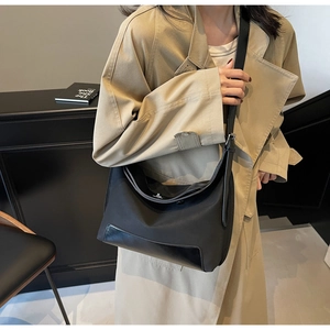 Detail view of black nylon hobo bag with leather base worn with a khaki trench coat