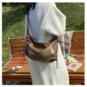 Close-up of soft brown leather texture and drawstring detail on the chic shoulder bag