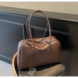 Dettaglio della borsa in pelle testa di moro con trama litchi su una sedia di legno nera