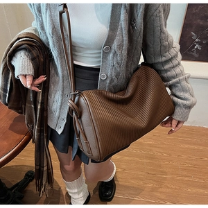 Detail of brown pleated texture on cylinder bag with minimalist strap for women