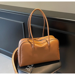 Dettaglio della borsa tote in pelle marrone martellata su una sedia con libri vintage