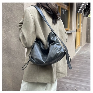 Outdoor street shot of a large black ruched crossbody bag paired with a khaki blazer