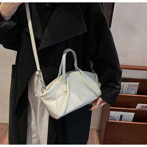 Detailed view of cream PU crossbody bag with unique horizontal pleats and metal hardware