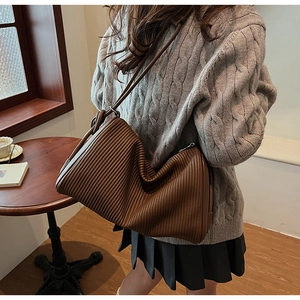 Close-up of pleated dark brown leather shoulder bag detail with elegant accordion texture