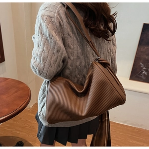 Detail of hobo bag featuring vertical pleated texture in deep caramel brown leather