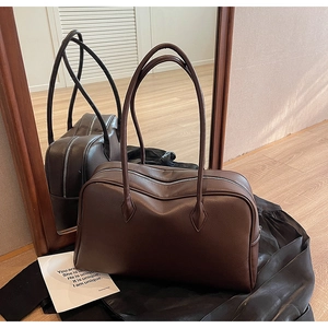 Dettaglio della borsa tote in pelle marrone scuro con doppia cerniera su legno