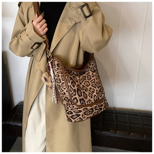 Detailed shot of leopard print large tote bag with brown leather strap on khaki coat