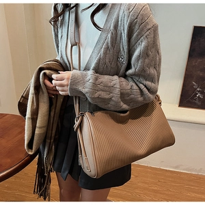 Detail of brown pleated shoulder bag showing vertical textures and knotted strap detail