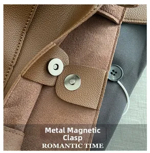 Detailed macro view of the metal magnetic clasp on brown lychee grain leather bag
