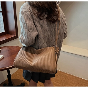 Detailed view of the brown pleated leather shoulder bag showing the vertical texture and knotted strap