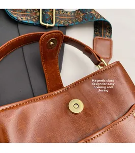 Detalle del cierre magnético en bolso tipo cubo de cuero marrón con correa retro