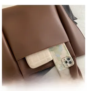 Close-up of a side pocket on a brown lychee textured leather tote with daily essentials