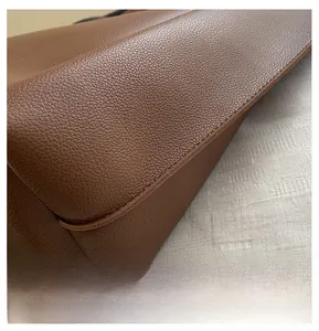 Close-up of brown litchi grain leather bag bottom showing precise stitching and texture