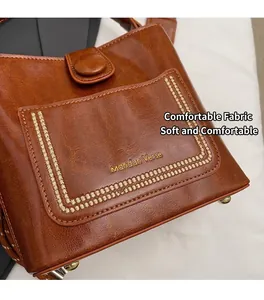 Detalle del bolso tipo cubo marrón vintage con textura de PU pulido y marca dorada