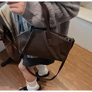 Dark brown pleated shell bag shown as a crossbody on model with casual urban styling