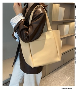 Lifestyle shot of a beige large capacity faux leather tote bag with front pocket detail