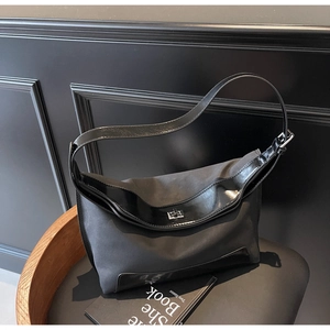 Close-up of black nylon and patent leather hobo bag with silver turn-lock buckle