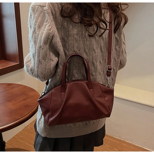 Detailed view of the dark red pleated shell bag featuring textured faux leather and straps
