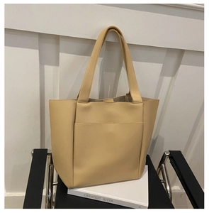Detail of minimalist cream large tote bag in soft PU leather on a black chair