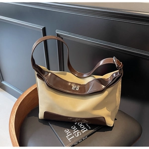 Detail of hobo bag with beige fabric, brown patent leather trim, and silver metal twist lock