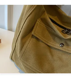 Detail of khaki canvas messenger bag showing texture, front pocket, and metal buckle