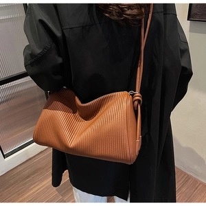 Detailed view of brown leather tote bag with vertical pleated texture on model