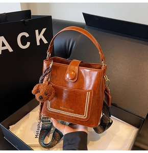 Detail der braunen Beuteltasche mit Perlenbesatz, Retro-Gurt und Bären-Anhänger