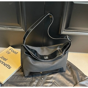 Detail of dark gray tote bag featuring patent leather trim and silver metal twist lock