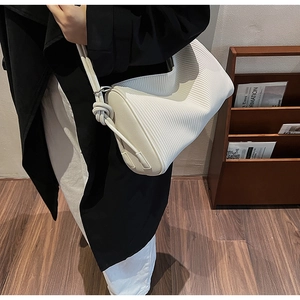 Detail view of a cream pleated underarm bag with unique rope knot strap on the shoulder
