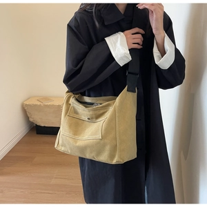 Detailed side view of the spacious canvas messenger bag in mustard yellow with white stitching