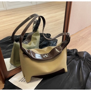 Detail of vintage khaki canvas hobo bag featuring brown patent leather trim and silver twist lock