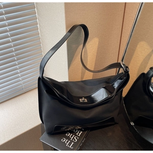 Detailed view of black nylon tote bag with silver metal swivel lock and leather trim