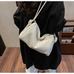 Detailed view of cream pleated shoulder bag with unique vertical texture and cord strap