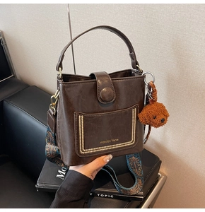 Details der braunen Bucket-Bag mit ethnischem Gurt und süßem Plüsch-Hundeanhänger