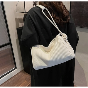 Close-up of cream white pleated hobo bag with vertical texture and silver zipper detail