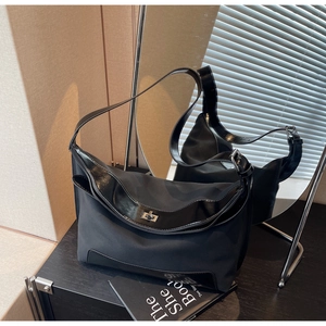 Detail of black nylon hobo bag with glossy trim and silver metal twist-lock buckle