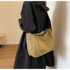 Detailansicht der khakifarbenen Segeltuchtasche mit weißen Nähten und Metallknopfklappe
