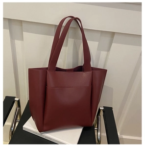 Detail of burgundy tote bag with front pocket on minimalist chair for office commute