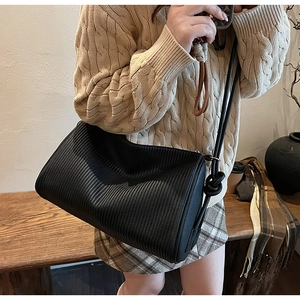 Detail of black textured shoulder bag with vertical pleats and knot strap detail
