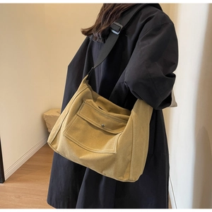 Details einer Canvas-Umhängetasche mit verstellbarem Gurt und Vordertasche in Senfgelb