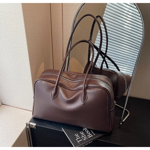 Dettaglio della trama in pelle marrone scuro con grana litchi su una borsa stile Boston