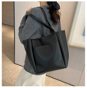 Detail of a large black pebbled leather tote bag with a front pocket for office commute