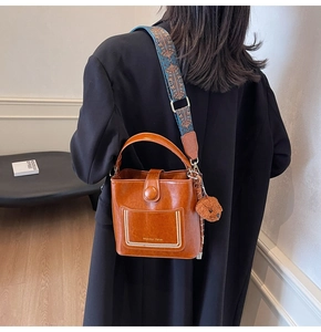 Braune Vintage-Beuteltasche mit Ethno-Gurt und Plüschbär-Anhänger am Model gezeigt