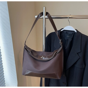 Detail of vintage brown tote bag with metal buckle closure and textured faux leather finish