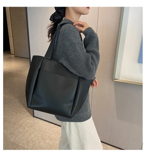 Side view of large black pebble leather tote bag with elegant pleated design for women
