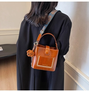 Braune Lederbeuteltasche mit vintage Blumenriemen und Plüschbär-Anhänger im Detail