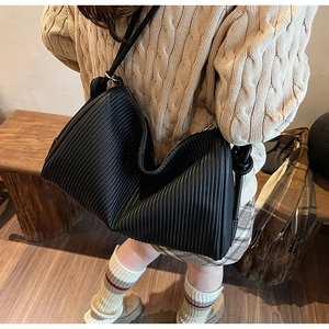 Close-up of black pleated faux leather shoulder bag with vertical textured ruffles