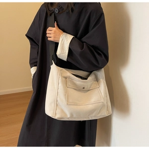 Große beige Canvas-Umhängetasche mit Fronttasche und schwarzem Riemen in Detailansicht