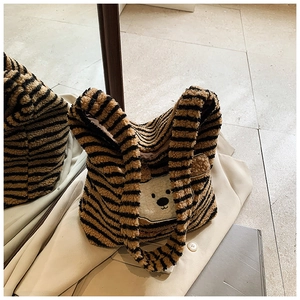Detailaufnahme der gestreiften Plüschtasche mit einem niedlichen Bären-Aufnäher auf dem Stoff